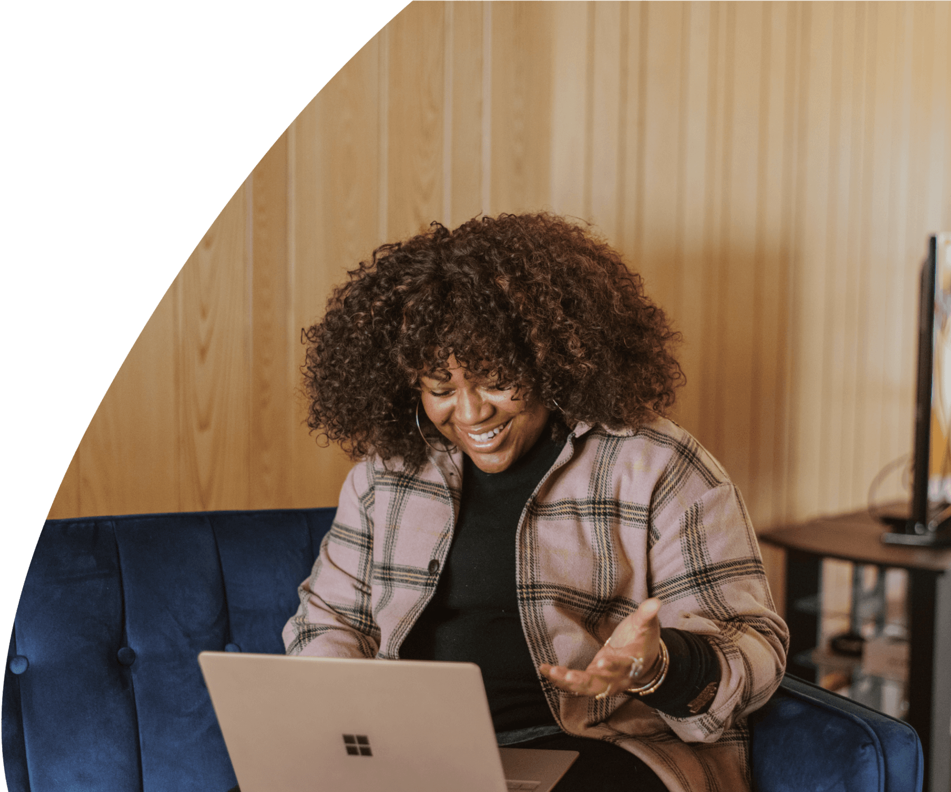 Woman sitting on a couch in front of her laptop, smiling